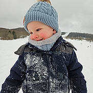 Eden a rejoint le concours — aidez-le/la à gagner de superbes lots ! child, toddler, winter_clothing, hat, pom_pom, gloves, snow, outdoor, cold_weather, smile, face, red_cheeks, jacket, nature, trees, hill, snowy_field, playful, cute, portrait
