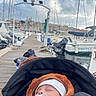 baby, sleeping, stroller, pacifier, hat, jacket, marina, dock, boats, water, sky, cloudy, rope, wooden_pier, outdoor, calm, infant, transport, harbor, relaxation