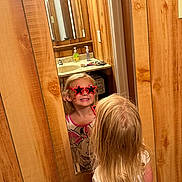 Nevaeh is registered to the contest to win money with this photo: bathroom, blonde_hair, child, funny_glasses, happy, indoor, long_hair, mirror, person, playful, red_glasses, reflection, reflection_glasses, sink, smiling, soap_dispenser, standing, star_shaped_glasses, white_shirt, wood_paneling