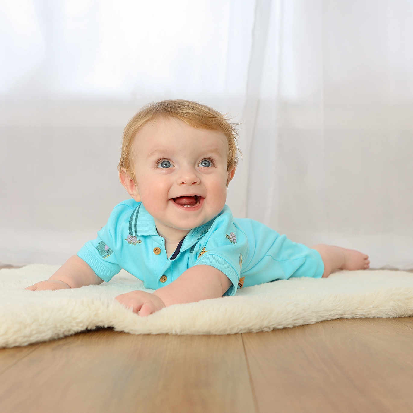 Wesley is registered to the contest to win money with this photo: baby, background, blue_clothing, child, curtain, cute, eyes, face, feet, floor, hands, happy, indoor, infant, light, lying_down, portrait, rug, smiling, wood_floor