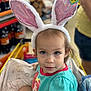 toddler, child, bunny_ears, shopping_cart, store, price_tag, blue_shirt, curious, face, person, indoor, clothing, cute, headwear, retail, baby, young_child, sitting, portrait, expression