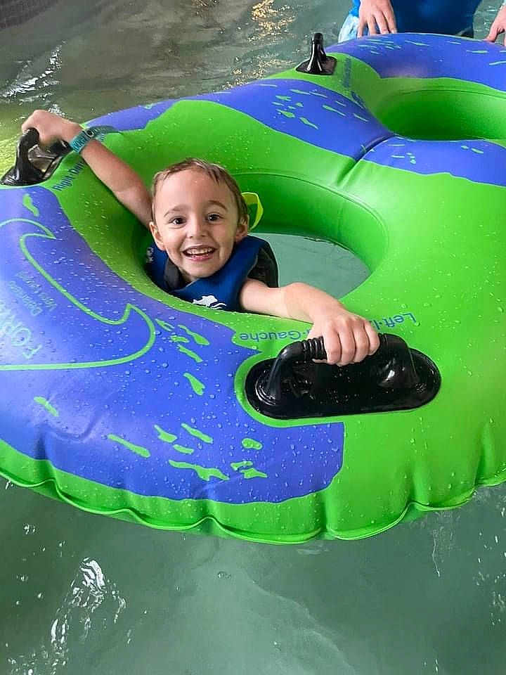 Dakota is registered to the contest to win money with this photo: boats_and_boating_equipment_and_supplies, child, chute, fun, games, grass, green, happy, inflatable, joy, leisure, outdoor_recreation, people_in_nature, person, personal_protective_equipment, play, recreation, smile, toddler, tubing