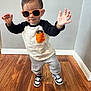 toddler, child, sunglasses, orange, black_and_white, shirt, pants, sneakers, standing, floor, wooden_floor, indoor, pose, hands_up, cute, fashion, person, casual, smile, hair