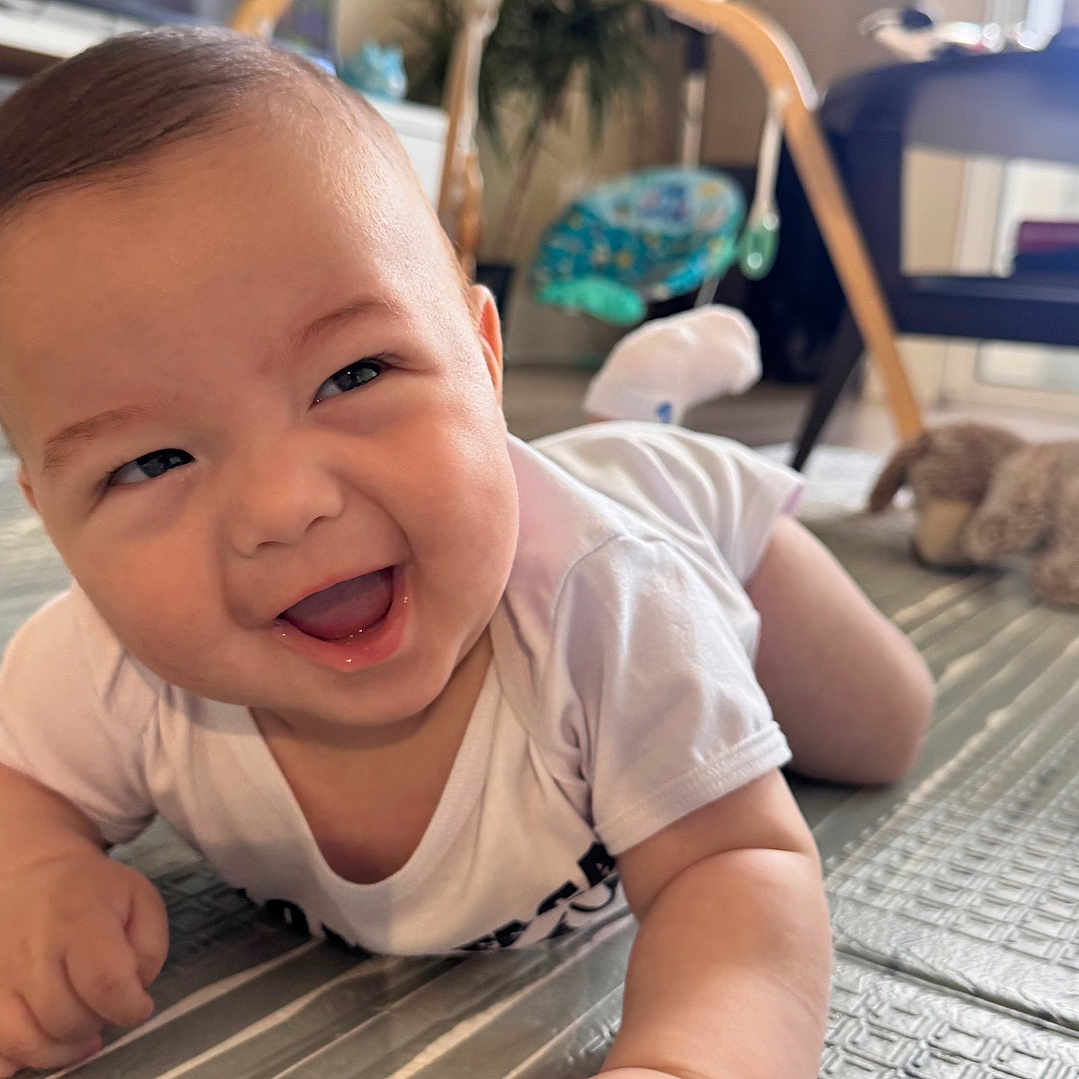 Noah is registered to the contest to win money with this photo: baby, smiling, indoor, mat, crawling, child, happy, toy, furniture, floor, person, cute, infant, playtime, home, bright, expression, toddler, clothing, skin