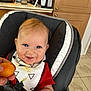 baby, smile, high_chair, bib, food, hand, kitchen, cabinet, orange_food, red_shirt, blue_eyes, messy, happy, infant, person, indoor, seat, cute, child, feeding