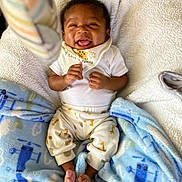 Uriah is registered to the contest to win money with this photo: baby, bib, blanket, blue_blanket, child, cozy, cute, family_love, feet, giraffe_pattern, hands, happy, indoor, infant, lying_down, portrait, smiling, soft_texture, warm, white_clothing