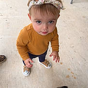 Raegan joined the competition — help win amazing prizes! toddler, child, headband, mustard_sweater, navy_pants, sneakers, concrete_floor, animal, goat, hand, looking_up, outdoor, curious, cute, small_child, footwear, person, pet, casual_clothing, baby
