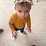 toddler, child, headband, mustard_sweater, navy_pants, sneakers, concrete_floor, animal, goat, hand, looking_up, outdoor, curious, cute, small_child, footwear, person, pet, casual_clothing, baby