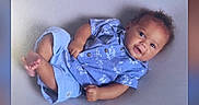Amanuel is registered to the contest to win money with this photo: baby, child, infant, blue_clothing, smiling, lying_down, portrait, cute, young_child, short_hair, happy, indoor, casual, one_person, looking_at_camera, light_background, baby_boy, playful, small_feet, relaxed