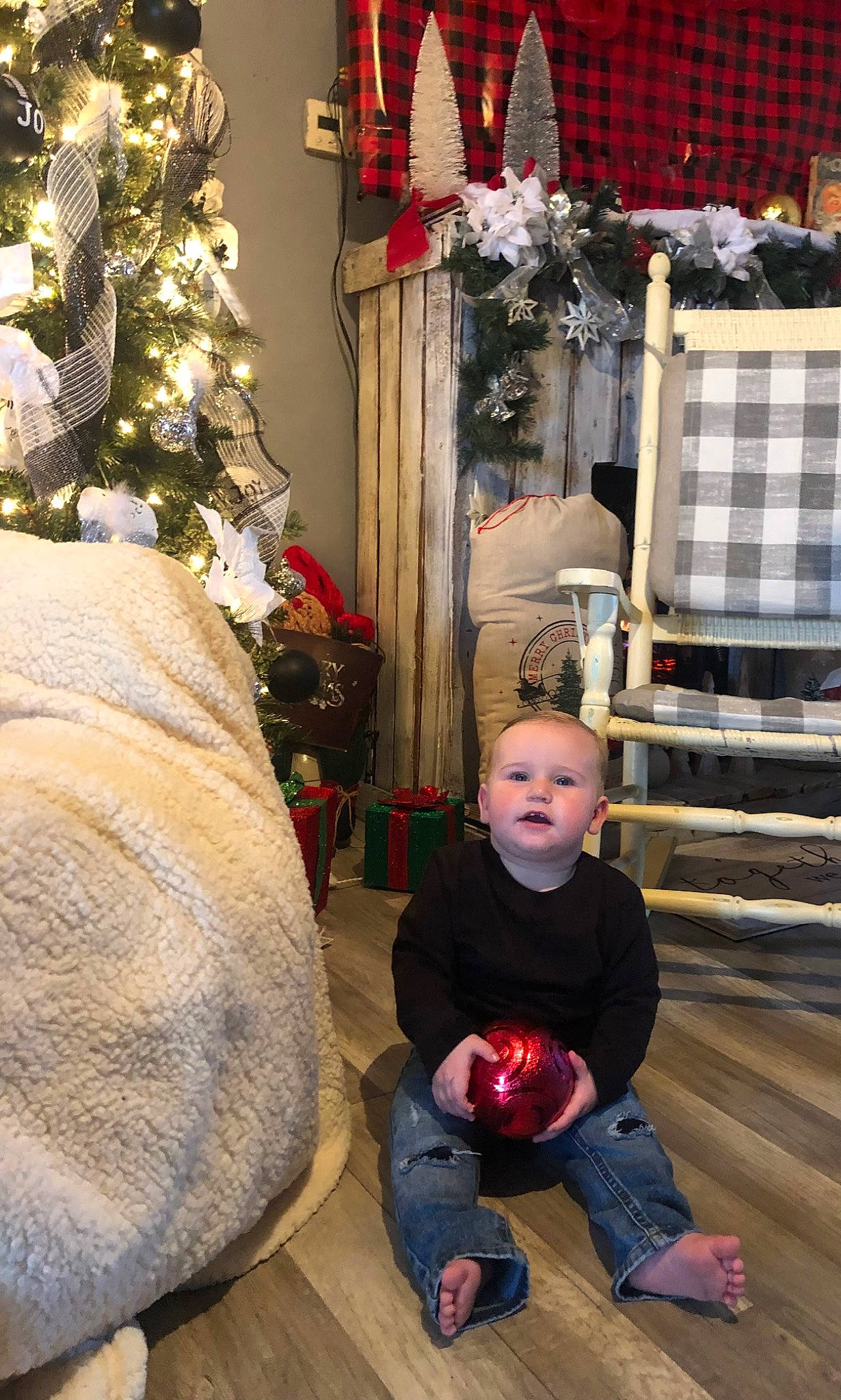 Aiden is registered to the contest to win money with this photo: black, christmas_decoration, christmas_ornament, christmas_tree, event, flooring, holiday, holiday_ornament, organ, ornament, people, person, photograph, red, snapshot, sneakers, standing, toddler, tree, white