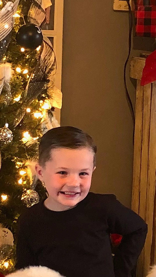 Kaysen joined the competition — help win amazing prizes! chin, christmas_decoration, christmas_ornament, christmas_tree, conifer, event, flash_photography, fun, happy, head, holiday, holiday_ornament, joy, ornament, person, plant, red, sitting, smile, standing
