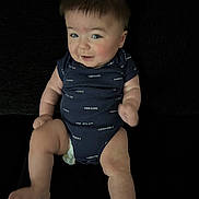 Izzy is registered to the contest to win money with this photo: baby, infant, child, onesie, blue_clothing, smile, sitting, cute, chubby, skin, face, happy, young, person, legs, arms, expression, indoor, portrait, diaper