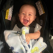 Giovanni joined the competition — help win amazing prizes! baby, smiling, blanket, car_seat, child, happy, infant, clothing, seatbelt, cute, portrait, person, sitting, indoors, toddler, head, face, baby_blanket, seat, comfort
