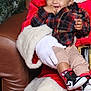 Anthony is registered to the contest to win money with this photo: toddler, child, santa_claus, beanie, plaid_shirt, sneakers, holiday, christmas_tree, leather_chair, gloves, red_clothing, smiling, happy, indoor, portrait, festive, cute, baby, person, seasonal