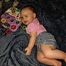 baby, child, smiling, pink_shirt, denim_shorts, toy, colorful_toy, blanket, indoor, happy, face, cute, infant, playful, young_child, lying_down, carpet, soft_texture, blue_blanket, portrait