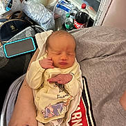 Tabitha is registered to the contest to win money with this photo: baby, bag, blanket, bottle, child, clothing, coca_cola, face, hands, home, indoor, infant, lap, newborn, onesie, photograph, portrait, relaxed, sitting, sleeping