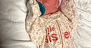 Tabitha is registered to the contest to win money with this photo: baby, bed, blanket, bottle_nipple, cozy, eyes_open, face, floral_clothing, indoors, infant, lying_down, mittens, newborn, onesie, pacifier, portrait, sleepwear, striped_cap, textile, white_bedding