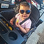 Melinda is registered to the contest to win money with this photo: baby, car, child, chips, concrete, cute, food, outdoor, parking_lot, person, pink_shirt, seat, seatbelt, smile, snack, stroller, sunglasses, sunlight, toddler, vehicle