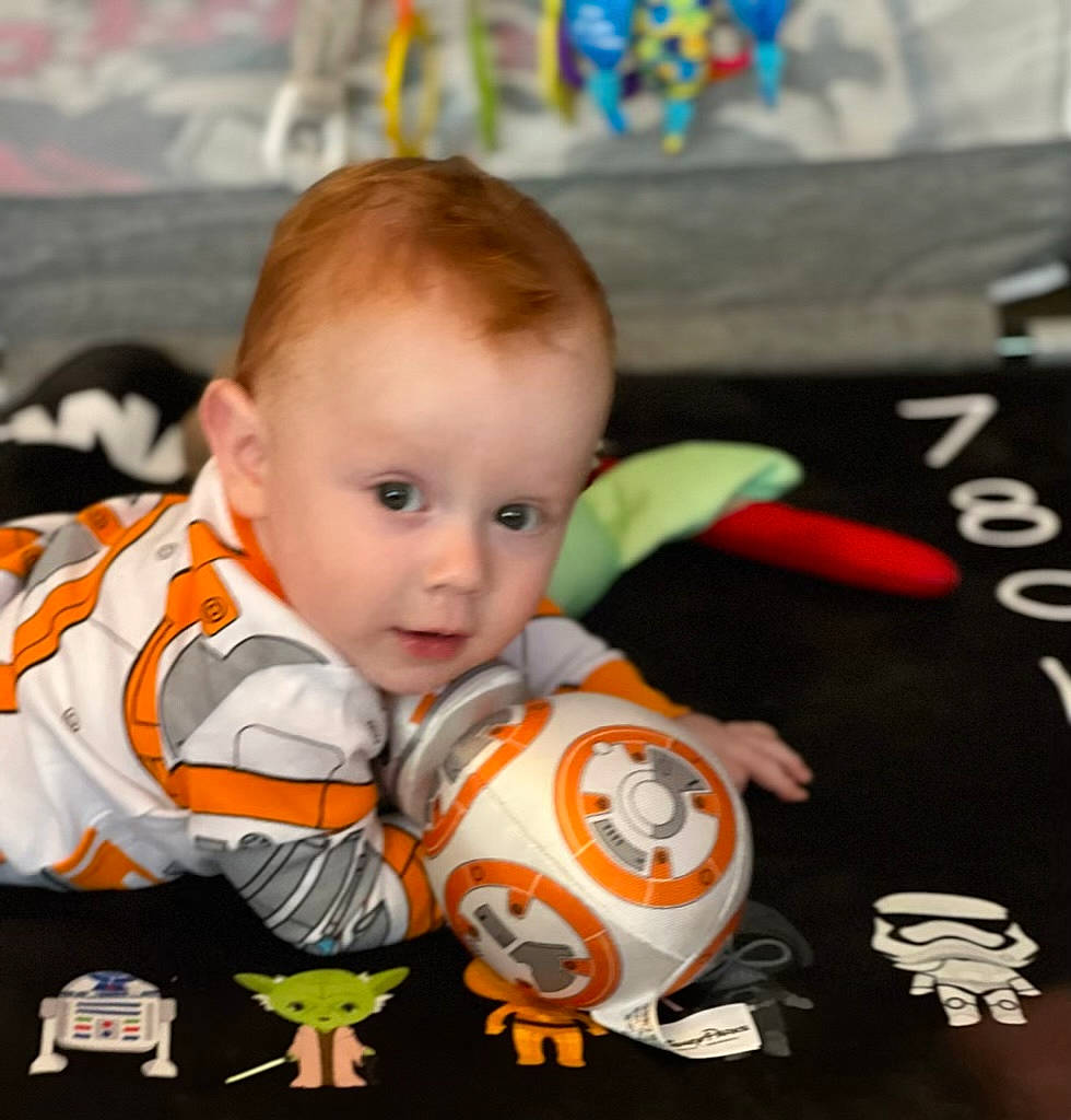 Anakin is registered to the contest to win money with this photo: baby, baby_playing_with_toys, baby_products, baby_toddler_clothing, baby_toys, cheek, child, eye, flooring, fun, happy, human_body, iris, orange, person, play, product, room, sitting, surprise