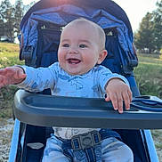 Kooper joined the competition — help win amazing prizes! baby, stroller, smiling, outdoor, child, grass, sunlight, blue_clothing, onesie, shark_pattern, happy, seatbelt, nature, trees, infant, cute, playful, daytime, park, baby_shoes