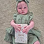 baby, infant, milestone_card, green_dress, headband, carpet, lying_down, hands, cute, child, portrait, indoors, soft_texture, milestone, four_months, person, young_child, expression, skin, clothing