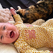 Jazmine joined the competition — help win amazing prizes! baby, bed, blanket, calico_cat, cat, close_up, cozy, cuddling, face, floral_pattern, hand, happy, infant, mouth_open, nursery, onesie, pet, pillow, smiling, yellow