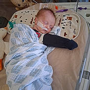 Larry is registered to the contest to win money with this photo: baby, sleeping, blanket, hospital, crib, nasal_tube, medical, plush_toy, groot, child, bed, comfort, resting, swaddled, cute, healthcare, infant, peaceful, indoor, soft