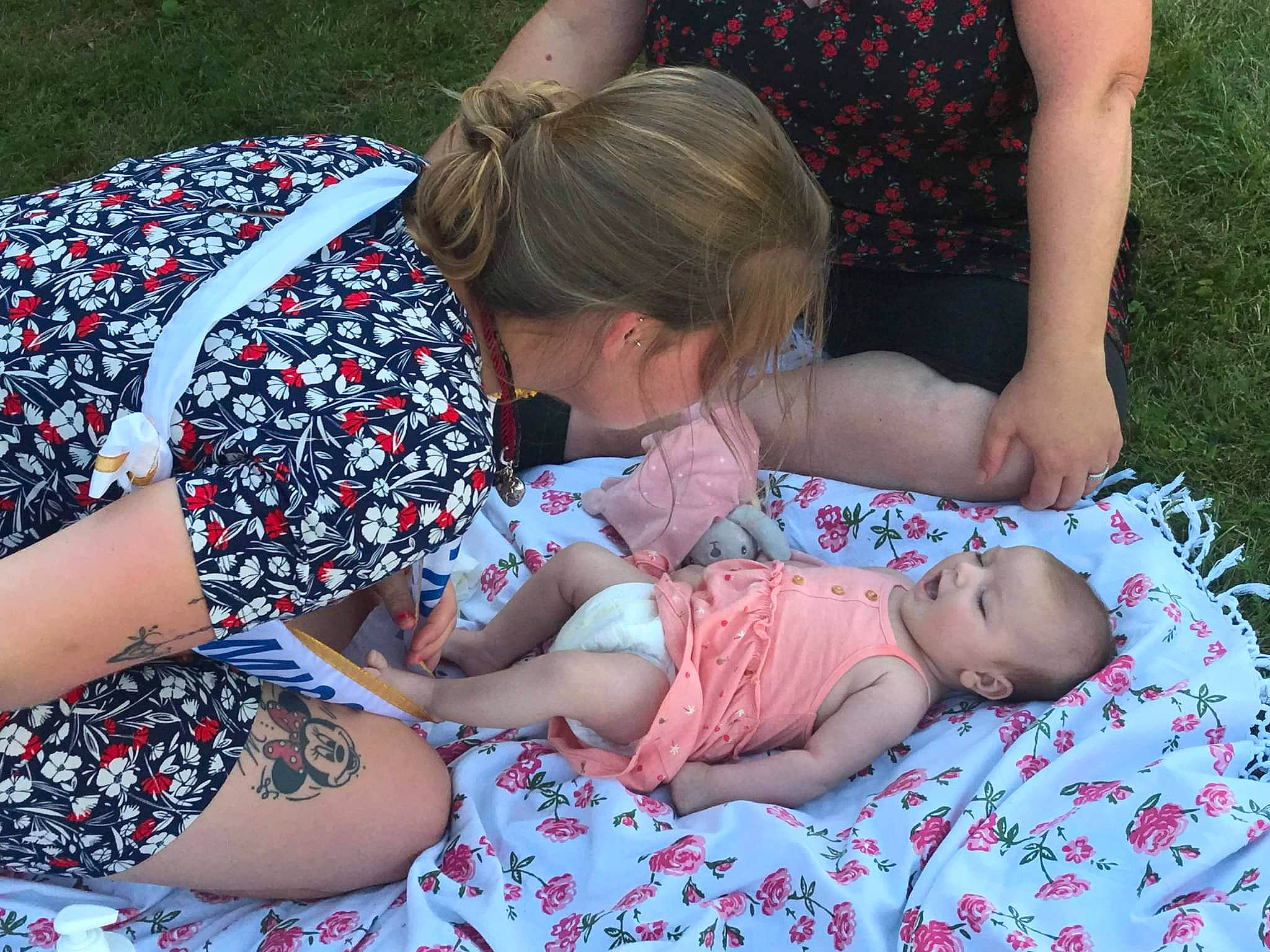 Inaya participe au concours pour gagner de l'argent avec cette photo : baby, baby_toddler_clothing, child, event, fun, glasses, grass, hairstyle, happy, interaction, lap, leisure, pattern, people_in_nature, person, pink, red, summer, thigh, toddler