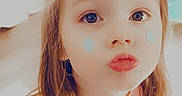 Annalisa is registered to the contest to win money with this photo: blue_teardrop_stickers, casual_clothing, child, cute, expression, face, floor, furniture, girl, home, indoor, jeans, long_hair, pink_shirt, playing, portrait, pouting, smiling, toys, young