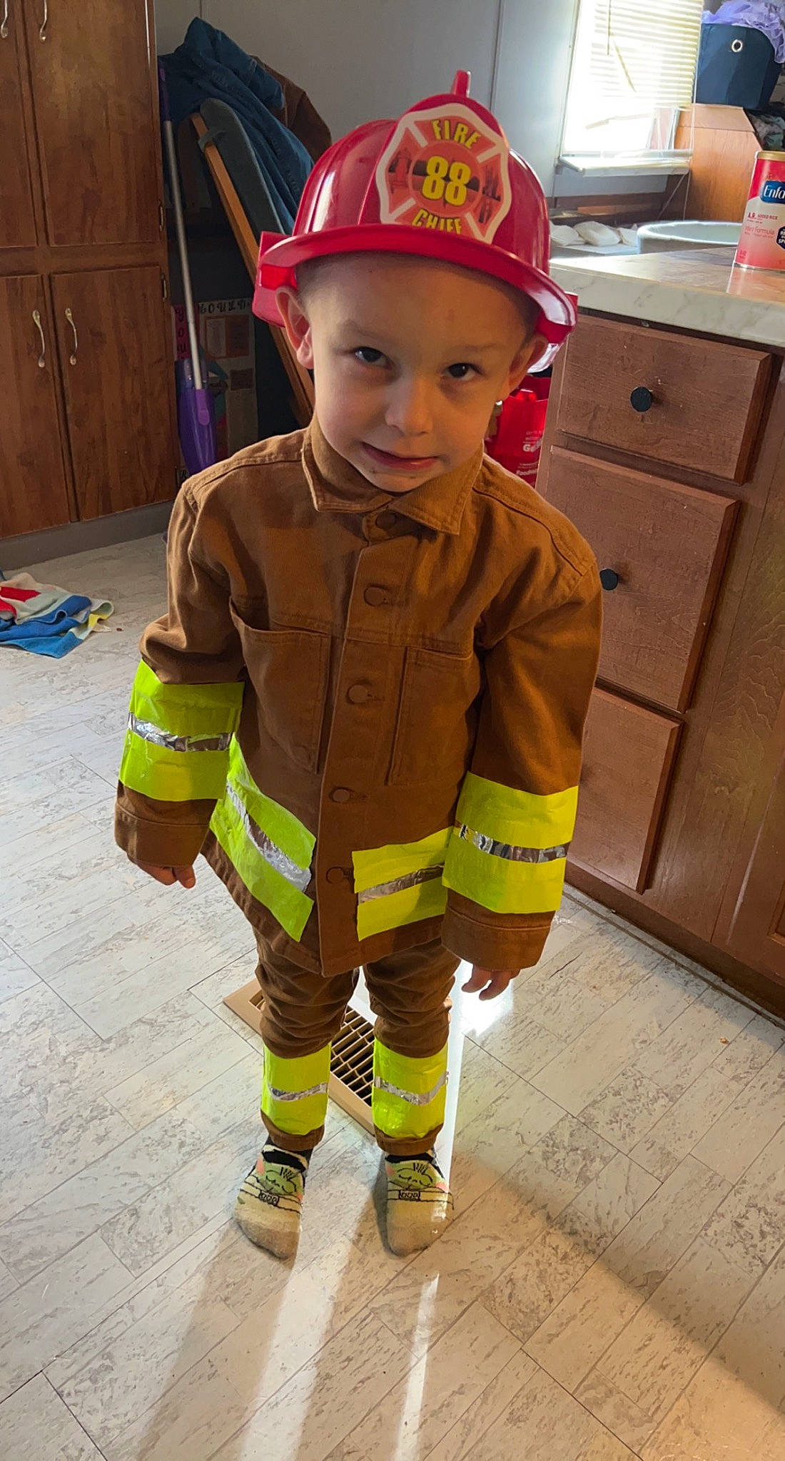 Braxton is registered to the contest to win money with this photo: baby, baseball_cap, cabinetry, cap, child, clothing, emergency_service, face, firefighter, hard_hat, head, headgear, headwear, high_visibility_clothing, joy, outerwear, person, personal_protective_equipment, sleeve, smile