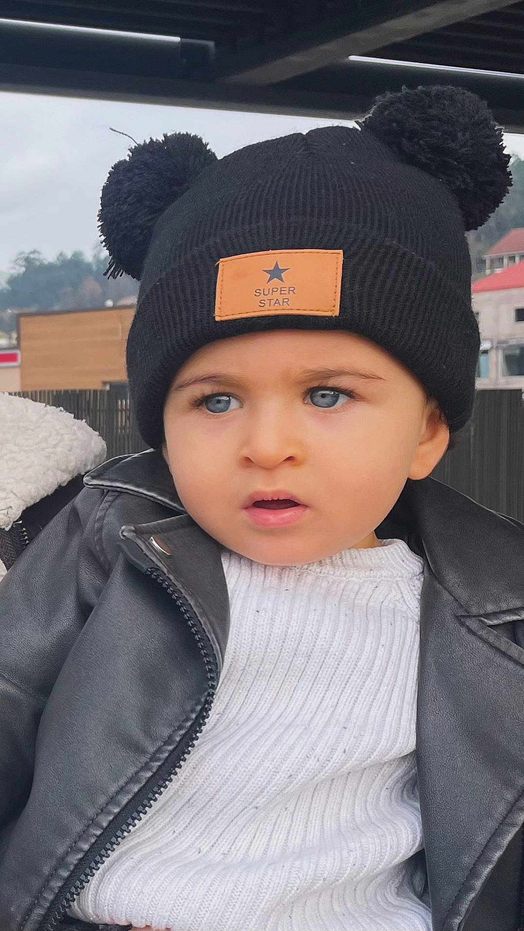 Rodrigo participe au concours pour gagner de l'argent avec cette photo : toddler, child, blue_eyes, black_hat, pom_poms, super_star_patch, white_sweater, black_jacket, outdoor, portrait, curious_expression, winter_clothing, face, headwear, cute, young_child, fashion, person, close_up, casual