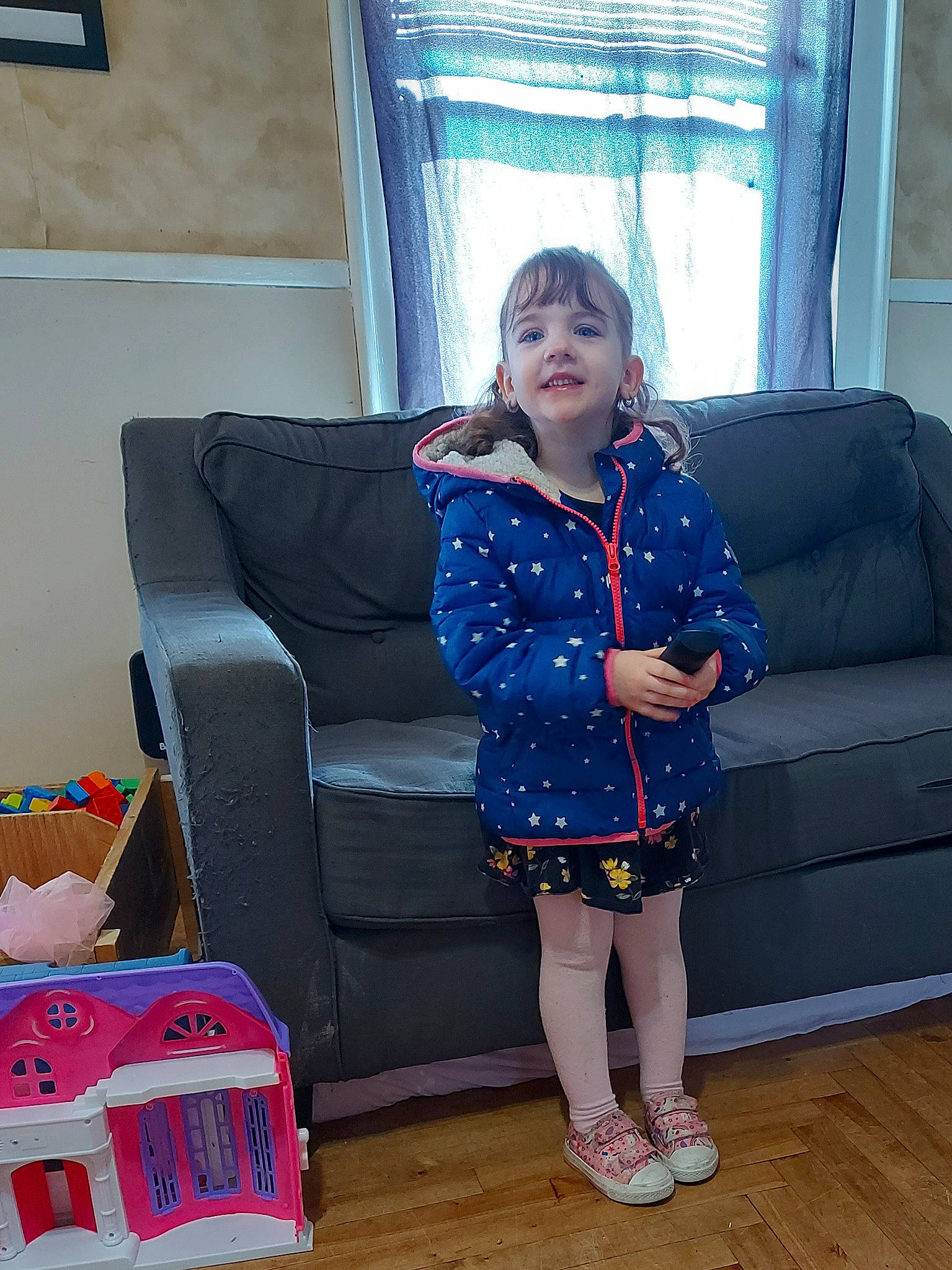 Jayme is registered to the contest to win money with this photo: baby_toddler_clothing, blue, comfort, couch, curtain, electric_blue, event, flooring, fun, human_leg, joy, knee, living_room, person, purple, sitting, sleeve, standing, studio_couch, thigh