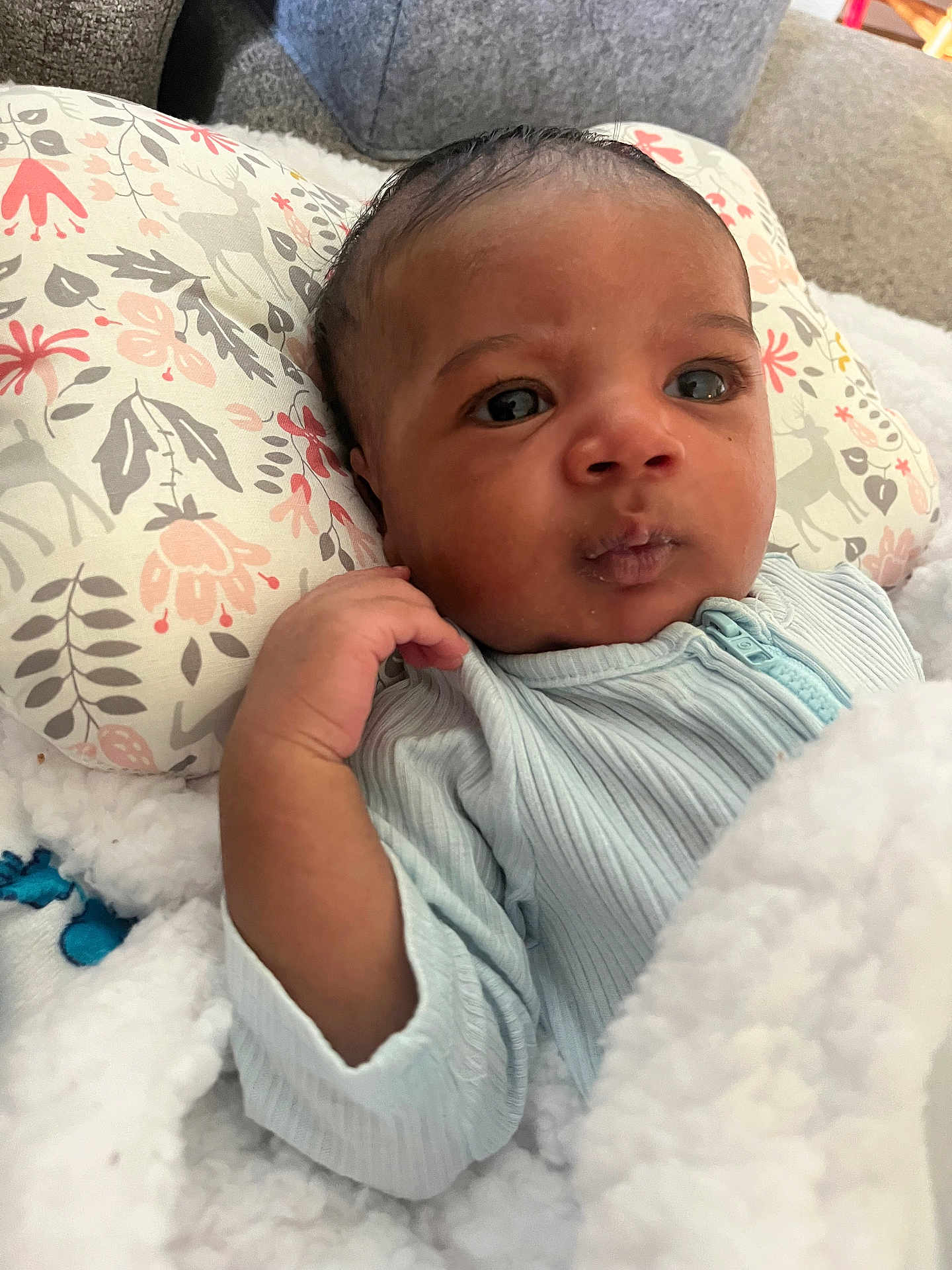 Elsadig is registered to the contest to win money with this photo: baby, infant, face, hand, blue_clothing, blanket, pillow, floral_pattern, indoors, portrait, cute, young_child, cozy, soft_texture, expression, curious, sleepwear, child, person, newborn