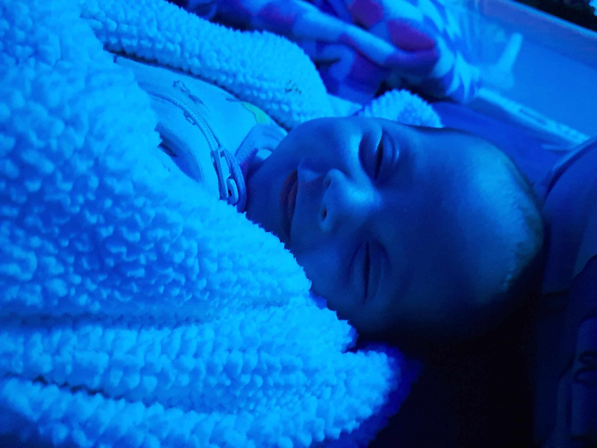 Kaylani is registered to the contest to win money with this photo: baby, blanket, blue_light, smile, cozy, sleepy, child, soft_texture, warm, face, portrait, indoor, cute, infant, wrapped, sleeping, peaceful, young, comfort, zipped_clothing