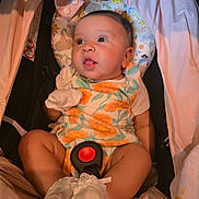 Kai is registered to the contest to win money with this photo: baby, infant, child, car_seat, floral_outfit, mittens, headrest, closeup, indoors, seatbelt, cute, portrait, sitting, young_child, expression, clothing, soft_lighting, comfort, fabric, small_person