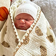 Noah participe au concours pour gagner de l'argent avec cette photo : baby, newborn, infant, sleeping, swaddled, blanket, beanie, hat, cozy, soft_texture, nursery, teddy_bear_pattern, pattern, fabric, portrait, close_up, adorable, cheeks, peaceful, rest