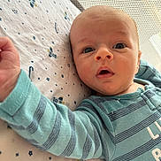 Ryder is registered to the contest to win money with this photo: baby, infant, onesie, striped_clothing, blue_clothing, lying_down, bed_sheet, patterned_sheet, stars, arm, face, eyes, mouth, skin, head, hand, indoor, closeup, person, child