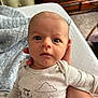 Ryder is registered to the contest to win money with this photo: baby, infant, onesie, clothing, face, hand, bed, blanket, furniture, wood, drawer, carpet, person, portrait, cute, indoors, expression, wide_eyes, human, newborn