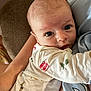 Ryder joined the competition — help win amazing prizes! baby, infant, person, face, eyes, clothing, onesie, arm, hand, blanket, couch, skin, adult, holding, closeup, indoor, portrait, expression, comfort, soft