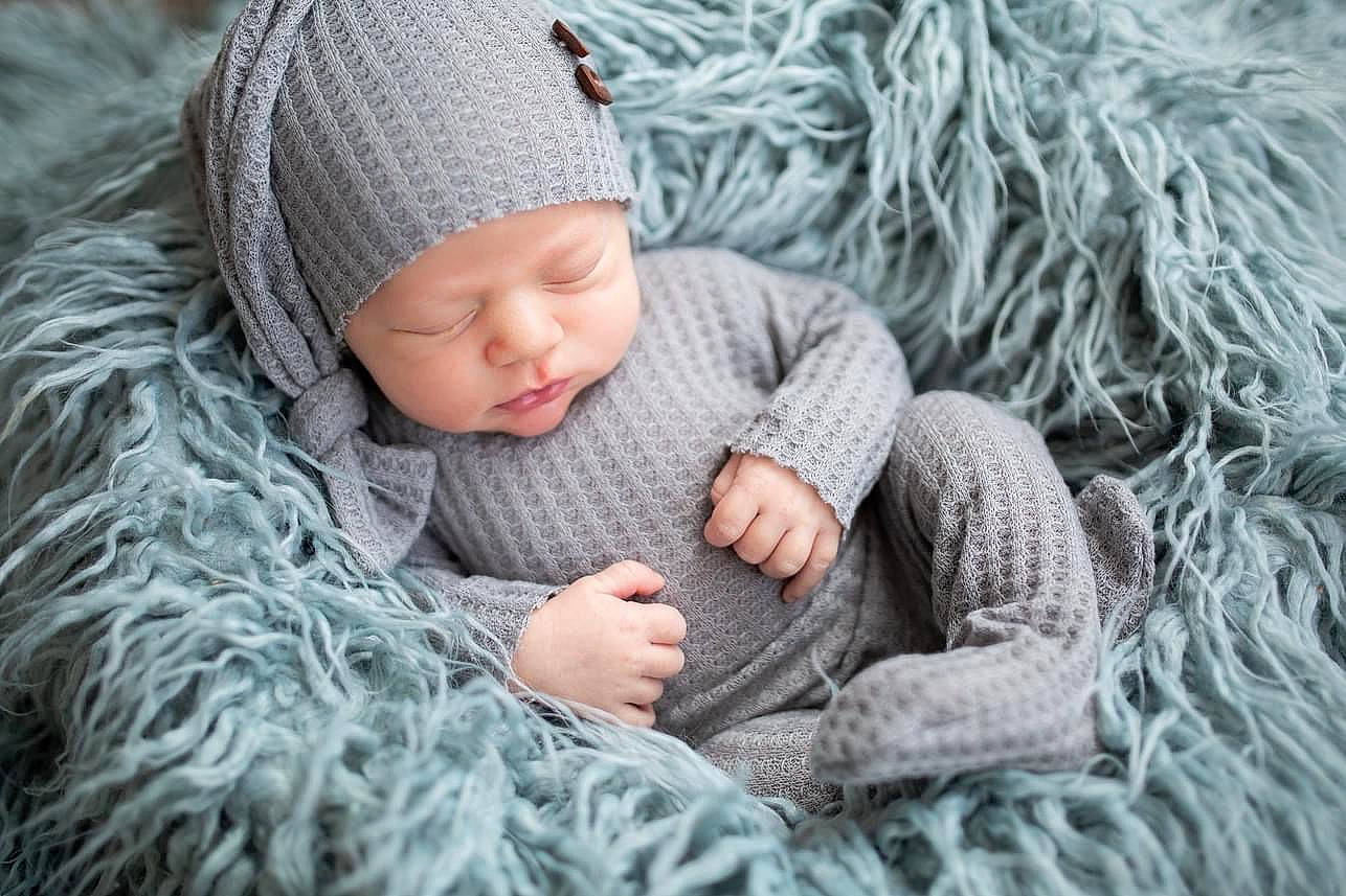 Koelton is registered to the contest to win money with this photo: baby, baby_toddler_clothing, cap, comfort, freezing, grass, grey, hand, hat, headgear, headwear, knit_cap, linens, pattern, person, plant, sitting, skin, toddler, tree