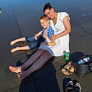 Yoni a rejoint le concours — aidez-le/la à gagner de superbes lots ! child, woman, outdoor, sunlight, reflection, barefoot, water, shoes, bag, can, fanta, sitting, casual_clothing, relaxing, family, summer, wet_surface, smiling, people, park