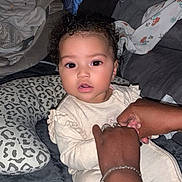 Inès participe au concours pour gagner de l'argent avec cette photo : adult, baby, blanket, child, clothing, comfort, couch, curly_hair, cushion, eyes, face, hands, holding, home, indoor, infant, person, sitting, skin, soft_fabric