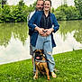 canine, casual_clothing, couple, dog, embrace, grass, greenery, happy, lake, leisure, nature, outdoor, pet, portrait, relaxation, scenic, smiling, summer, sunlight, trees