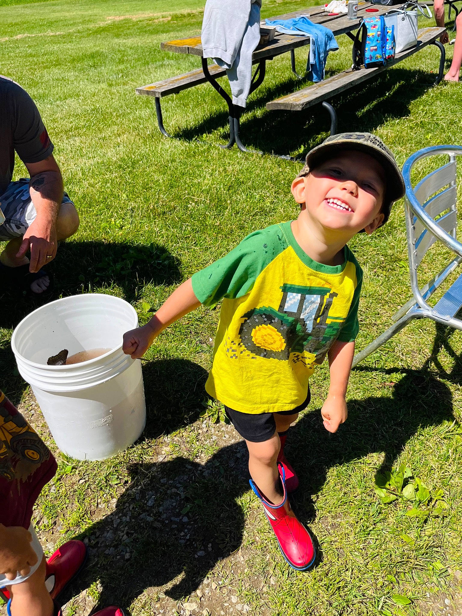 Landen is registered to the contest to win money with this photo: bucket, chair, child, fun, garden, gardening, grass, green, headwear, joy, lawn, leisure, people_in_nature, person, plant, recreation, shorts, smile, sneakers, soil