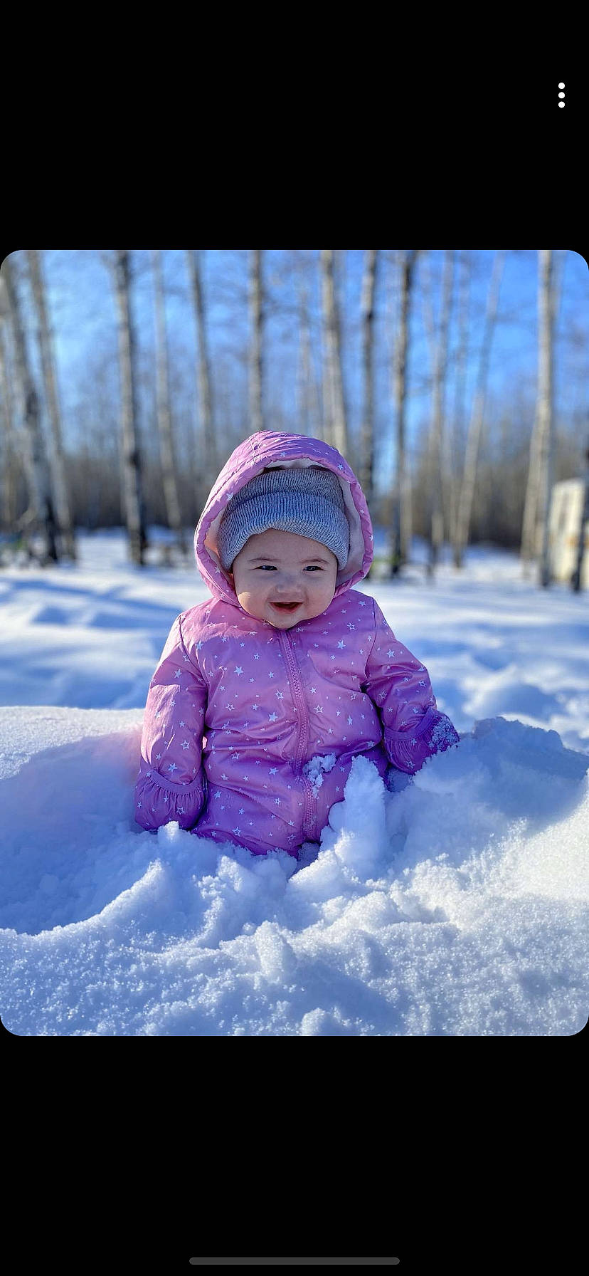 Collins is registered to the contest to win money with this photo: baby, bonnet, child, freezing, fun, headgear, headwear, leisure, outerwear, person, photograph, photography, pink, play, playing_in_the_snow, purple, recreation, sky, smile, snow