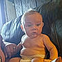 Johnny is registered to the contest to win money with this photo: baby, diaper, child, couch, leather, hand, indoor, wood_paneling, window, natural_light, person, skin, sitting, curious, infant, adult_hand, furniture, face, expression, casual