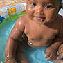 Ahnya-Ann joined the competition — help win amazing prizes! baby, child, water, pool, inflatable_pool, wet, smile, skin, hand, arm, face, person, indoor, tile_floor, background, toy, colorful, animal_print, playful, fun