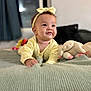 Aurora is registered to the contest to win money with this photo: baby, child, infant, yellow_clothing, headband, smiling, plush_toy, stuffed_animal, bed, blanket, indoor, portrait, cute, happy, soft_lighting, knitted_blanket, person, cuddly_toy, infant_girl, cozy
