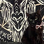 Stella joined the competition — help win amazing prizes! black_cat, cat, bow_tie, green_eyes, tribal_art, wall_art, black_background, leopard_print, animal_pattern, indoor, pet, feline, portrait, sitting, decor, sofa, furniture, closeup, artistic, animal_face