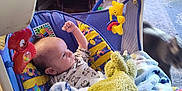 Theodore is registered to the contest to win money with this photo: baby, infant, baby_swing, blanket, toy, yellow_toy, raised_fist, face, indoor, furniture, chair, cat, blurred_cat, colorful, patterned_clothing, wooden_floor, cushion, home, child, curious